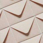 Artistic arrangement of beige envelopes creating a geometric pattern from above view.
